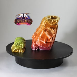 May include: A 3D printed miniature of a character wearing a layered, multi-colored outfit. The miniature is on a black circular base. The miniature is painted in shades of red, orange, yellow, and green. The miniature is from the Fates End MMF547 collection.