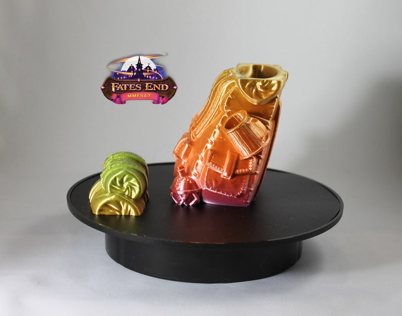 May include: A 3D printed miniature of a character wearing a layered, multi-colored outfit. The miniature is on a black circular base. The miniature is painted in shades of red, orange, yellow, and green. The miniature is from the Fates End MMF547 collection.