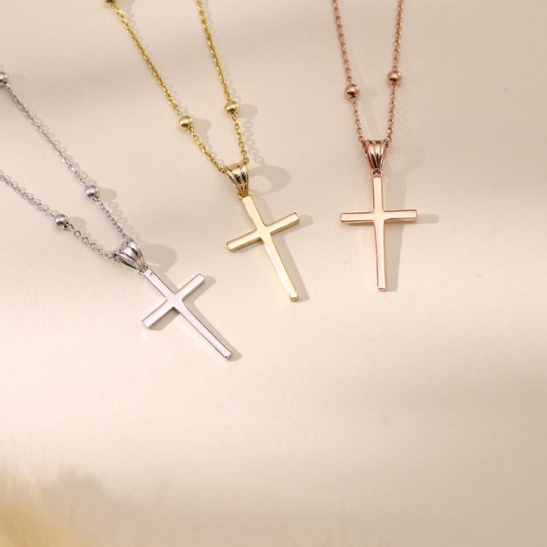 Op de afbeelding: Drie gouden kettingen met kruisen en verschillende kleuren kettingen. De kettingen zijn zilver, goud en ros&eacute;goud. De kruisen zijn allemaal even groot en even gevormd.