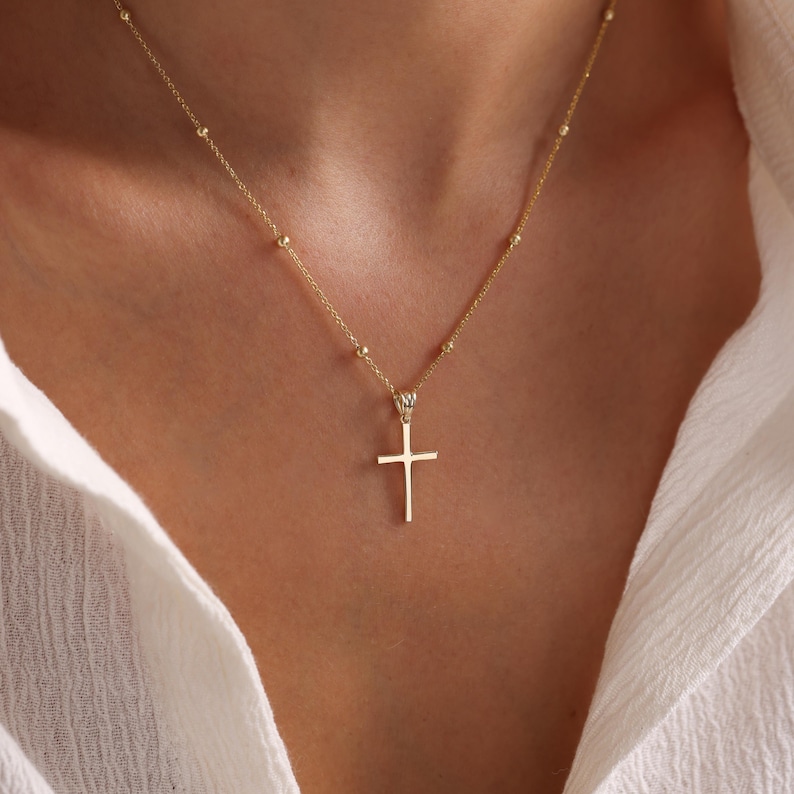 Op de afbeelding: Een gouden ketting met een klein gouden kruisje als hanger.