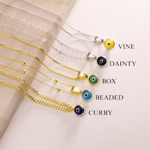 May include: A collection of gold and silver necklaces with colorful evil eye pendants. The necklaces have different chain styles, including box, beaded, and curb chains. The pendants are in various colors, including yellow, black, green, blue, and navy blue.
