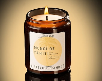 May include: A brown glass candle jar with a white label. The label has a yellow circle with a palm tree and the text "MONOÏ DE TAHITI" in black. The text "Cire végétale Fabrication artisanale" is also on the label in black. The text "L'ATELIER D'ANDRÉ" is on the label in black.