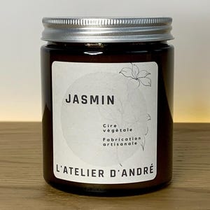 Peut inclure: Un bocal en verre brun avec un couvercle argenté. L'étiquette indique "JASMINE" et "Cire végétale Fabrication artisanale L'ATELIER D'ANDRÉ".