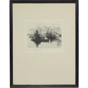 May include: A monochrome etching of a harbour scene, presented in a black wooden frame. The artwork shows boats, buildings, and cranes along the water's edge. The artist's signature is visible at the bottom of the print.