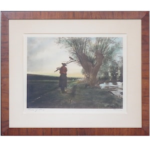 May include: A framed print of a painting depicting a person in a field with a willow tree and a river in the background. The person is carrying a rake and a shovel on their shoulder. The print is titled "Turn of Day".