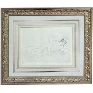 May include: A framed artwork featuring a pencil sketch of a reclining figure. The artwork is presented within a gold-toned, ornate frame, with a double matting in neutral tones. The sketch depicts a person resting on a pillow.