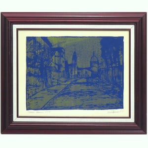 Könnte beinhalten: Ein gerahmter Druck mit einer Straßenansicht in Blau und Olivgrün mit Gebäuden und Bäumen. Das Kunstwerk befindet sich in einem dunkel rotbraunen Holzrahmen mit einem cremefarbenen Passepartout. Handschriftlicher Text ist unten zu sehen.