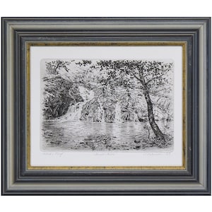 Peut inclure: Gravure en noir et blanc d'une scène de cascade, encadrée dans un cadre en bois gris et doré. L'œuvre représente une cascade, un arbre et un plan d'eau. Le cadre a une bordure intérieure dorée et une bordure extérieure grise.