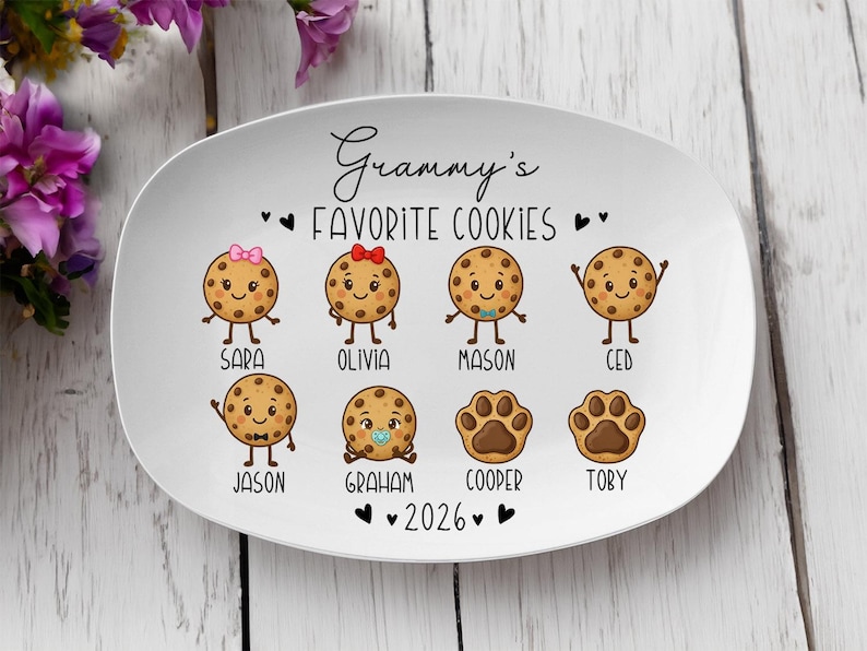 Peut inclure: Assiette ovale en c&eacute;ramique blanche avec le texte "Grammy's Favorite Cookies" et l'ann&eacute;e 2026. L'assiette pr&eacute;sente des personnages de biscuits de dessins anim&eacute;s avec des noms comme Sara, Olivia, Mason et Ced. Les biscuits ont des bras, des jambes et des expressions faciales.