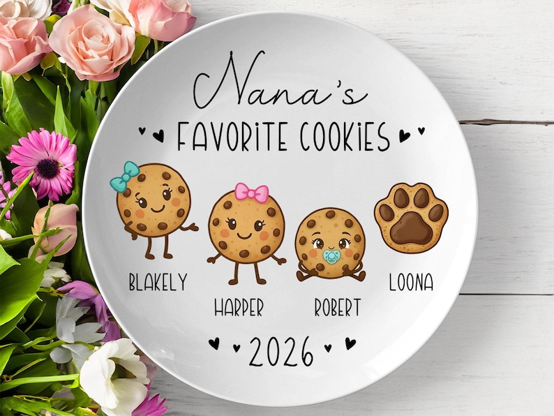 Peut inclure: Assiette en c&eacute;ramique blanche avec l'inscription "Nana's Favorite Cookies" et les noms Blakely, Harper, Robert et Loona. L'assiette pr&eacute;sente des personnages de biscuits de dessins anim&eacute;s et une empreinte de patte. L'ann&eacute;e 2026 est &eacute;galement affich&eacute;e.