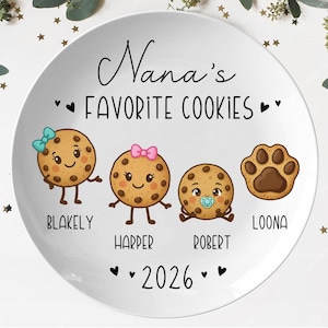 Peut inclure: Une assiette en c&eacute;ramique blanche avec le texte "Nana's Favorite Cookies" en &eacute;criture noire. L'assiette pr&eacute;sente des biscuits de dessin anim&eacute; avec des visages et des noms : Blakely, Harper, Robert et Loona. L'ann&eacute;e "2026" est &eacute;galement affich&eacute;e.