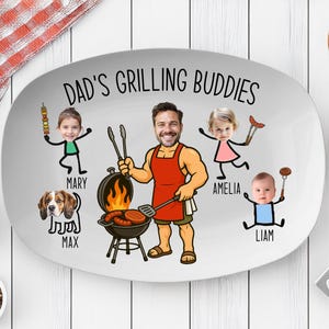 Peut inclure: Plat ovale avec l'inscription &laquo; Dad's Grilling Buddies &raquo; et des illustrations de dessins anim&eacute;s d'un homme faisant un barbecue, de trois enfants et d'un chien. Le plat est blanc avec un bord gris.