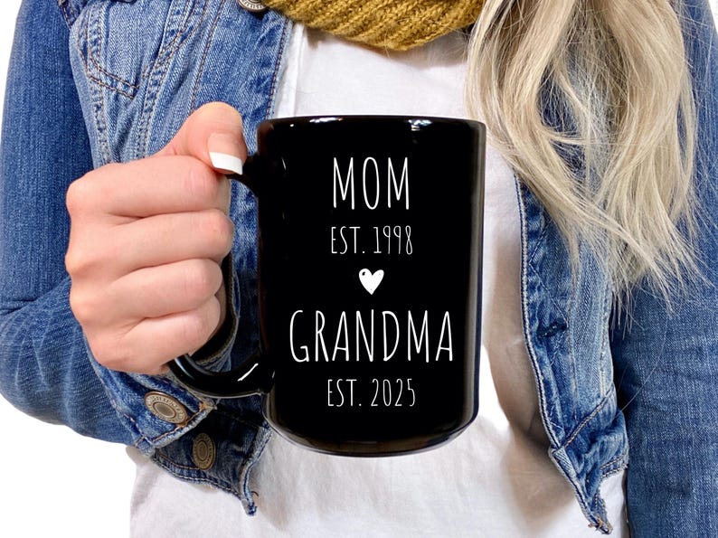 May include: Black ceramic mug with white text that reads "MOM EST. 1998" with a small white heart and "GRANDMA EST. 2025"
