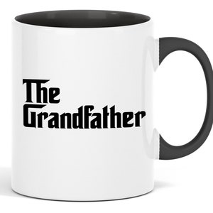 Op de afbeelding: Witte keramische mok met een zwarte binnenkant en handvat. De mok toont de tekst "The Grandfather" in een vetgedrukte, zwarte letter. Het ontwerp is gecentreerd op de buitenkant van de mok en biedt een klassieke en eenvoudige esthetiek.