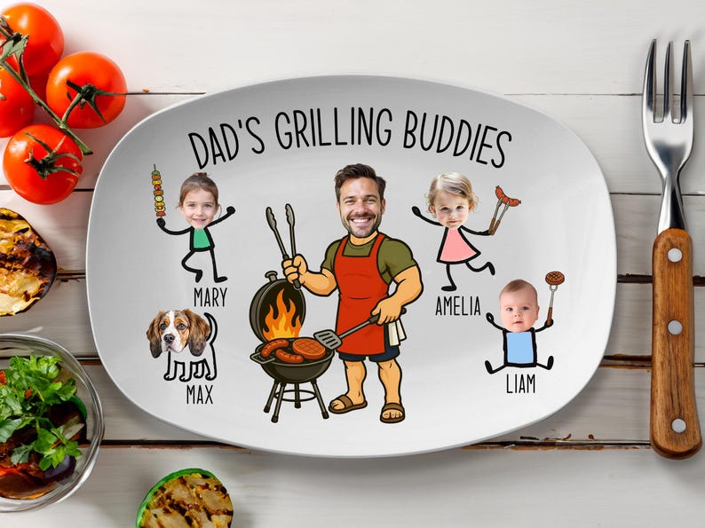 Peut inclure: Assiette ovale blanche avec le texte "DAD'S GRILLING BUDDIES" et des illustrations de dessins anim&eacute;s d'un homme faisant un barbecue avec sa famille et un chien. L'assiette a une fourchette et des tomates sur le c&ocirc;t&eacute;.