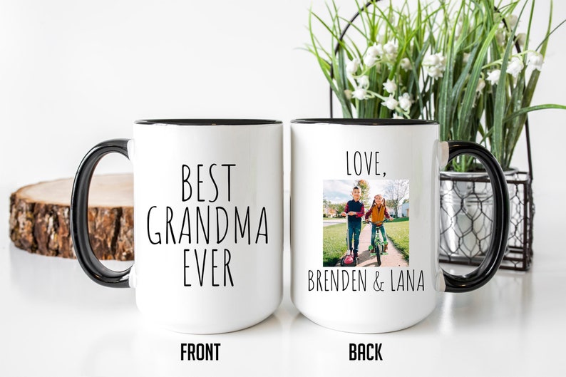 May include: White ceramic mug with a black rim and handle. The front of the mug says "BEST GRANDMA EVER". The back of the mug says "LOVE, BRENDEN & LANA" and has a photo of two children on scooters.