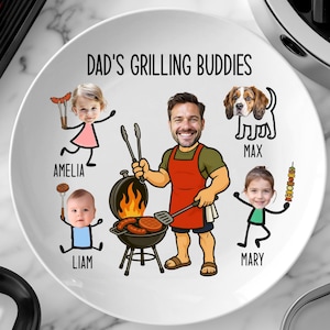 Peut inclure: Assiette en c&eacute;ramique blanche avec le texte "DAD'S GRILLING BUDDIES" et des illustrations de dessins anim&eacute;s d'un homme, d'enfants et d'un chien. L'homme fait griller des aliments sur un barbecue. L'assiette est un cadeau personnalis&eacute;.