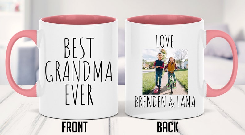 May include: White ceramic mug with a pink rim and handle. The front of the mug says "Best Grandma Ever". The back of the mug has a photo of two children on scooters and says "Love Brenden & Lana".
