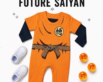 May include: An orange and navy blue long-sleeve baby romper featuring a printed brown belt and a circular emblem with black Japanese text on the chest. The text "RAISED ON LOVE. TRAINED TO WIN. FUTURE SAIYAN" appears above the romper with three orange spheres.