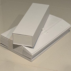 May include: A stack of white cardboard boxes, one of which is taller and narrower than the others. The boxes are all plain white with no markings or designs.