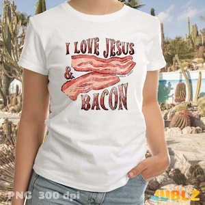 Puede incluir: Camiseta blanca con el texto "I love Jesus & Bacon" en letras rojas y marrones. El texto est&aacute; rodeado por un gr&aacute;fico de dos rebanadas de tocino.