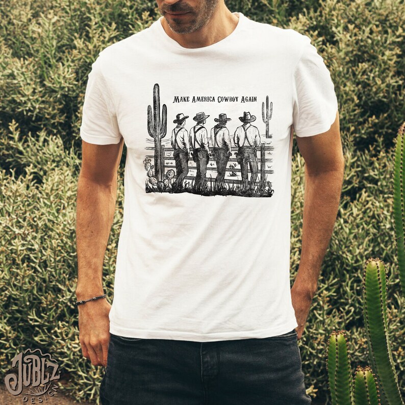 May include: A white t-shirt with a black and white illustration of four cowboys standing in front of a fence with the text "Make America Cowboy Again".