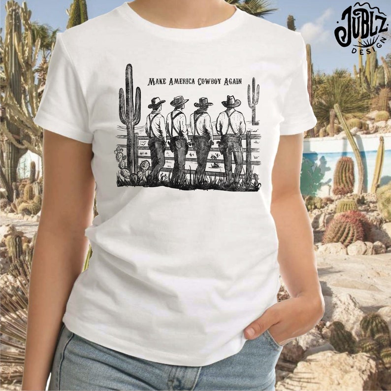 May include: A white t-shirt with a black and white illustration of four cowboys standing in front of a fence with the text "Make America Cowboy Again".