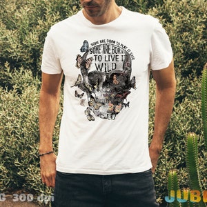 May include: White t-shirt with a skull graphic made of butterflies. The skull has a floral design and the text "SOME ARE BORN TO PLAY IT SAFE SOME ARE BORN TO LIVE IT WILD".