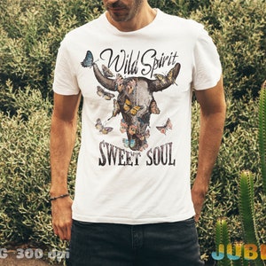 May include: White t-shirt with a graphic of a bull's head with butterflies and the text "Wild Spirit Sweet Soul".