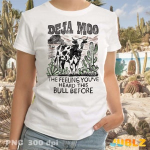 以下が含まれることがあります： 「Deja Moo」と「The feeling you've heard this bull before」のテキストが書かれた、牛とサボテンのヴィンテージスタイルのグラフィックが描かれた白いTシャツ。
