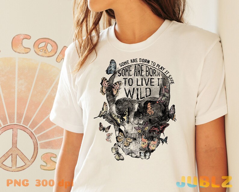 May include: White t-shirt with a skull graphic and butterflies. The skull has the text "Some are born to play it safe. Some are born to live it wild." printed on it.
