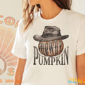 May include: White t-shirt with a graphic of a pumpkin wearing a cowboy hat. The text "Howdy Pumpkin" is printed below the pumpkin.