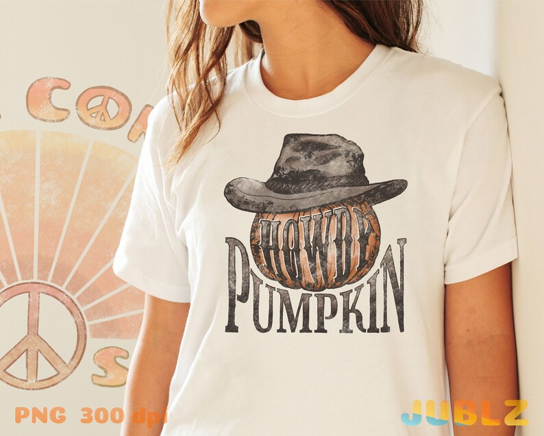May include: White t-shirt with a graphic of a pumpkin wearing a cowboy hat. The text "Howdy Pumpkin" is printed below the pumpkin.
