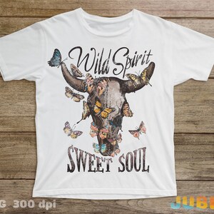 May include: White t-shirt with a brown bull skull design with colorful butterflies and the text "Wild Spirit Sweet Soul".