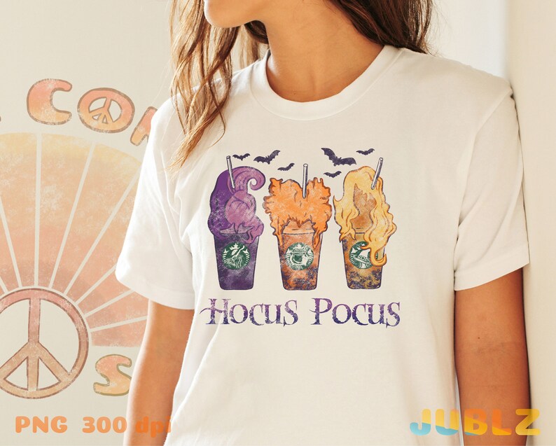 May include: White t-shirt featuring a vintage-style graphic of three Halloween-themed coffee cups with the text "Hocus Pocus" underneath.