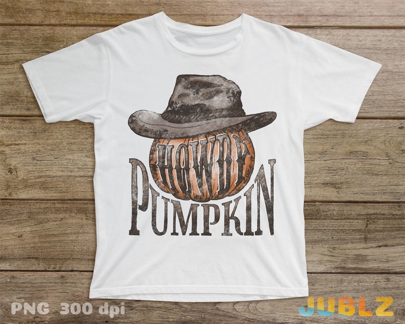 May include: White t-shirt with a brown and black cowboy hat on top of a pumpkin with the text "Howdy Pumpkin" printed on the front.