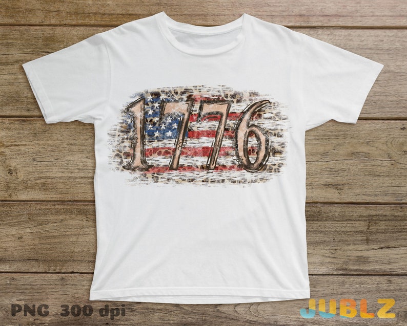 May include: White t-shirt with a distressed American flag design and the number 1776.