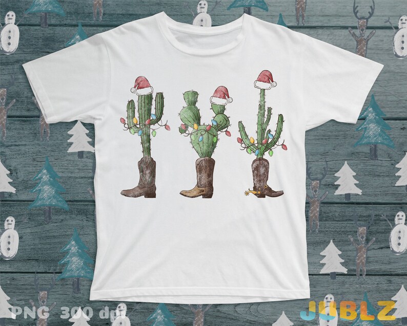 K&ouml;nnte beinhalten: Wei&szlig;es T-Shirt mit einem Weihnachtskaktus-Design. Der Kaktus tr&auml;gt einen Weihnachtsmann-Hut und hat Weihnachtslichter um sich herum. Der Kaktus tr&auml;gt Cowboystiefel.