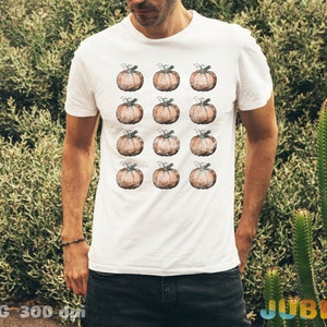 Puede incluir: Camiseta blanca con un patr&oacute;n de 12 calabazas marrones. Las calabazas est&aacute;n dispuestas en cuatro filas de tres.