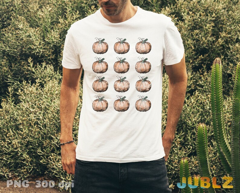Puede incluir: Camiseta blanca con un patr&oacute;n de 12 calabazas marrones. Las calabazas est&aacute;n dispuestas en cuatro filas de tres.