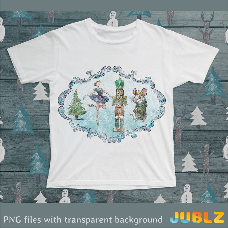 May include: A white t-shirt with a blue and green design featuring a ballerina, a nutcracker, and a mouse. The design is surrounded by a decorative frame.