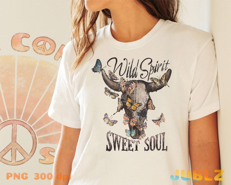 May include: White t-shirt with a graphic of a cow skull with butterflies and the text "Wild Spirit Sweet Soul".