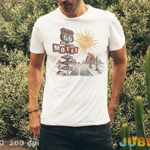 May include: White t-shirt with a vintage-style illustration of a desert road sign that reads "Route 66 Vacancy Motel".