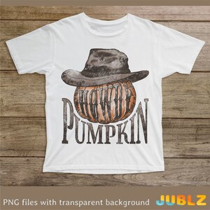 May include: White t-shirt with a graphic of a pumpkin wearing a cowboy hat. The text "Howdy Pumpkin" is printed below the pumpkin.