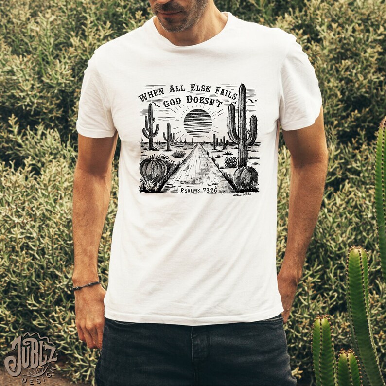 May include: White t-shirt with a black and white illustration of a desert landscape with cacti and a road. The text "When all else fails God doesn't" is written above the illustration. The text "Psalms 73:26" is written below the illustration.