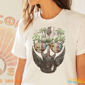 May include: White t-shirt with a graphic of a guitar with sunglasses and palm trees. The text "Paradise City" is above the guitar.