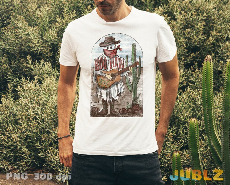 May include: White t-shirt with a vintage illustration of a skeleton playing a guitar in a desert landscape. The skeleton is wearing a cowboy hat and bandana. The text "Boo Haw" is printed on the shirt.