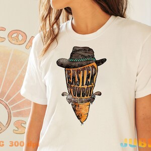 May include: White t-shirt with a graphic of a carrot wearing a cowboy hat and a belt with the text "Easter Cowboy".