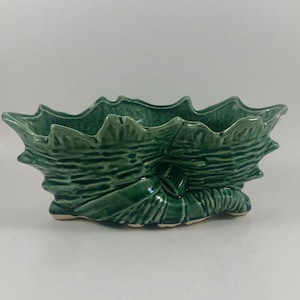 Könnte beinhalten: Ein grüner Keramik-Pflanztopf in Blattform mit strukturierter Oberfläche.