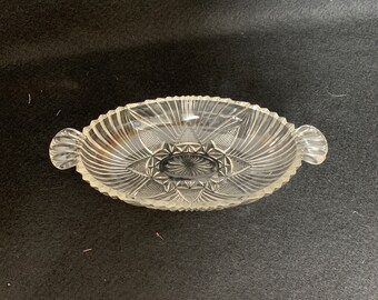 May include: A clear glass serving dish with two handles. The dish has a decorative, cut-glass pattern.